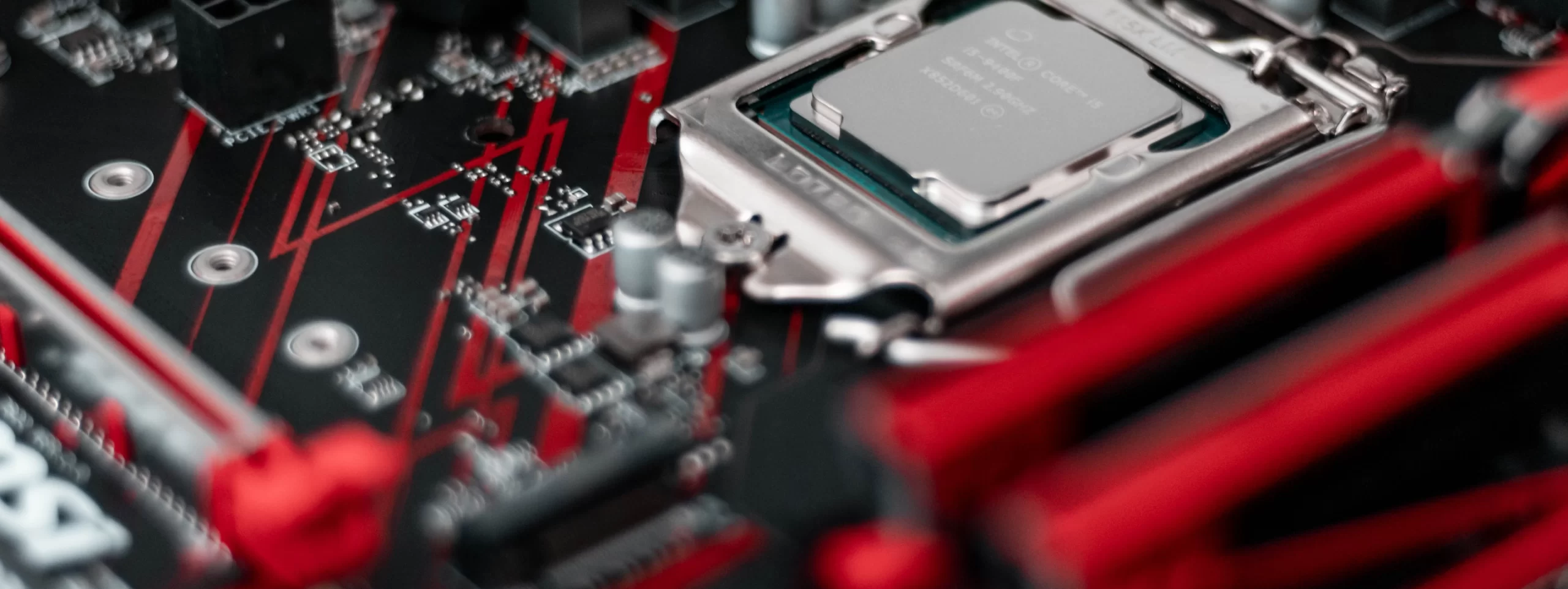 A close up of a motherboard with red and black components, highlighting the electronics supply chain.