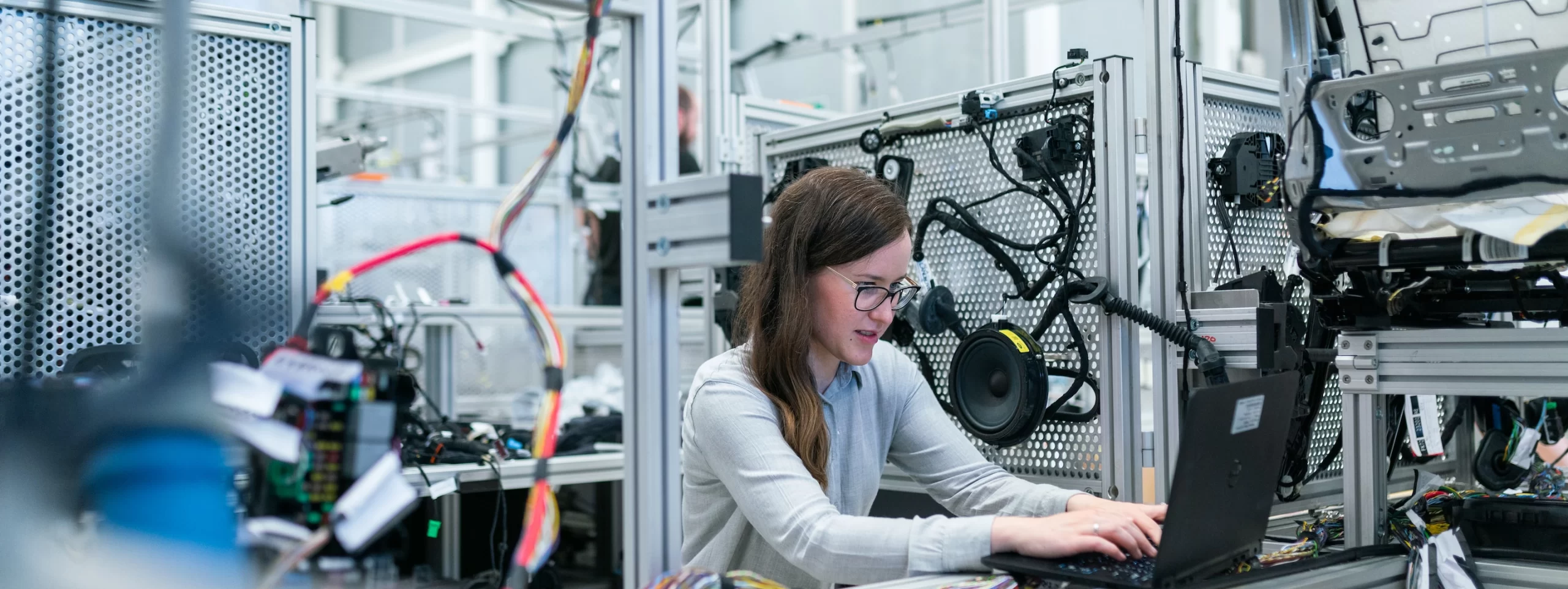 A woman engaged in manufacturing logistics operating a laptop in a factory.